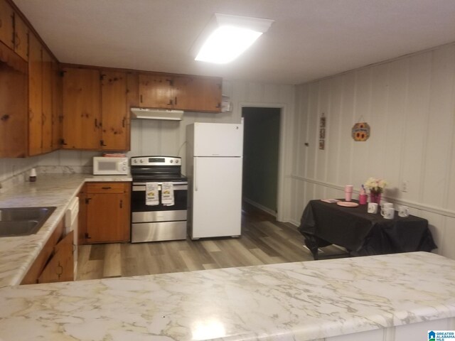 kitchen featuring kitchen peninsula, white appliances, light wood-type flooring, and sink