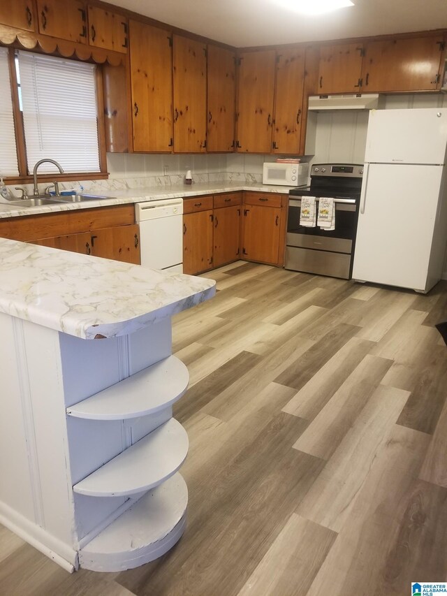 kitchen featuring light stone counters, light hardwood / wood-style floors, backsplash, white appliances, and sink