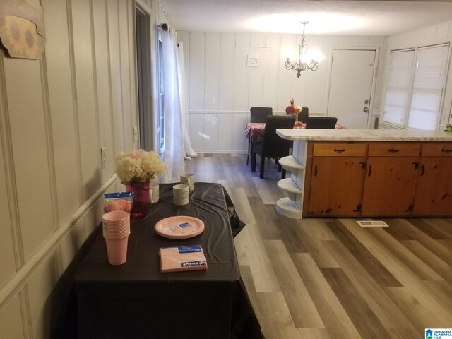 kitchen featuring kitchen peninsula, a notable chandelier, hardwood / wood-style floors, and pendant lighting