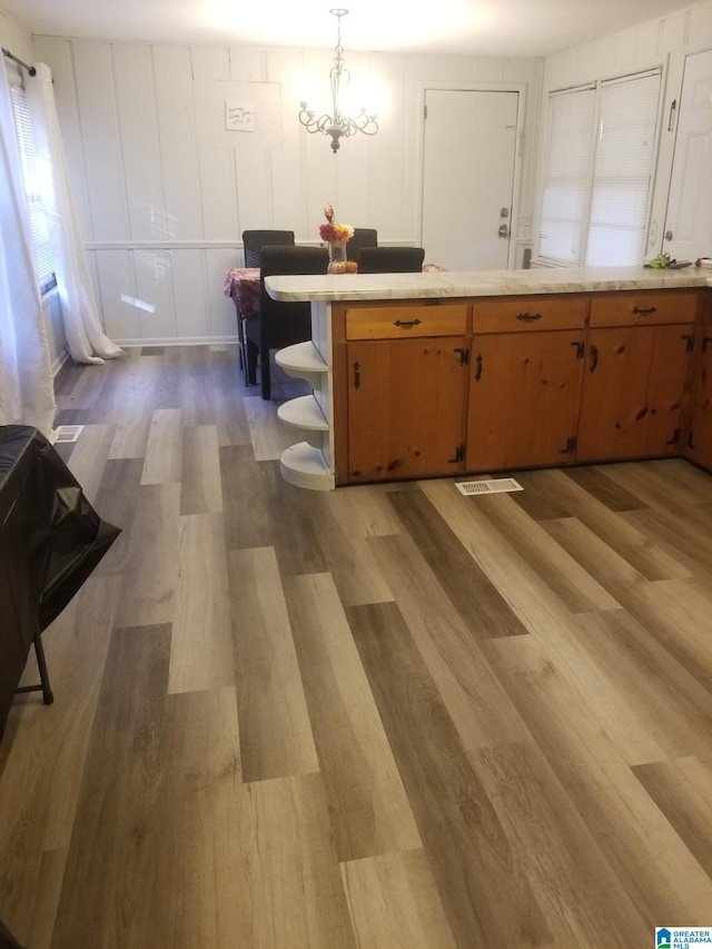 kitchen with pendant lighting, light hardwood / wood-style floors, and a notable chandelier