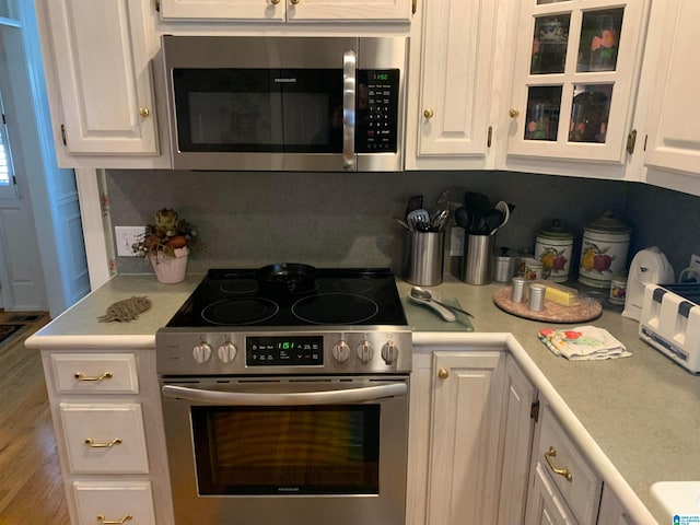 kitchen with hardwood / wood-style flooring, appliances with stainless steel finishes, and white cabinetry