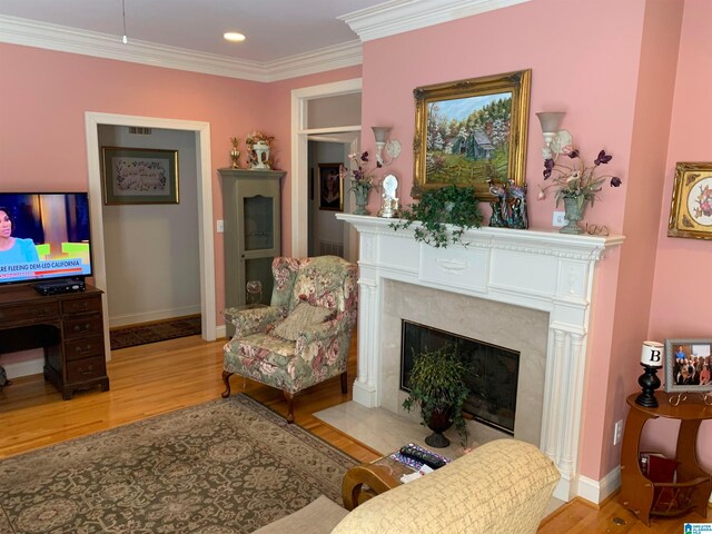 living room featuring a premium fireplace, crown molding, and light hardwood / wood-style flooring