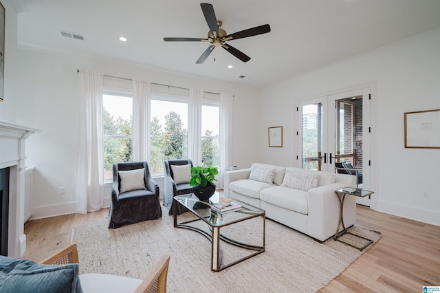 living room with ornamental molding, light hardwood / wood-style floors, french doors, and ceiling fan