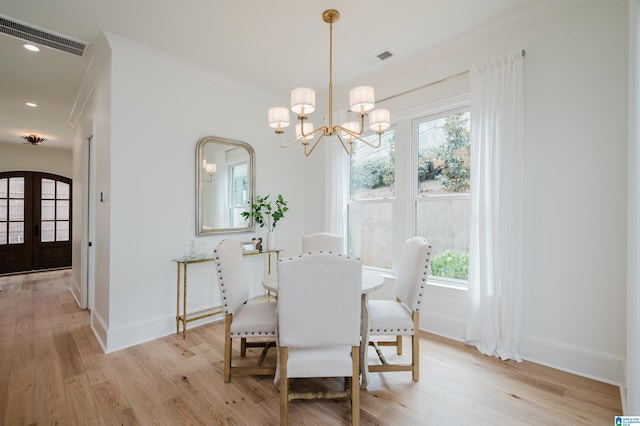 dining room with french doors, a notable chandelier, crown molding, and light wood-type flooring