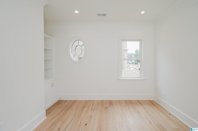 empty room with crown molding and light hardwood / wood-style floors