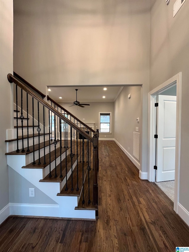 stairway with hardwood / wood-style floors and ceiling fan