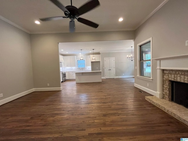 unfurnished living room with ceiling fan with notable chandelier, crown molding, a fireplace, and dark wood-type flooring