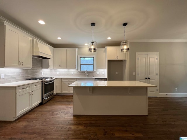 kitchen with white cabinets, a kitchen island, stainless steel range with gas cooktop, and premium range hood