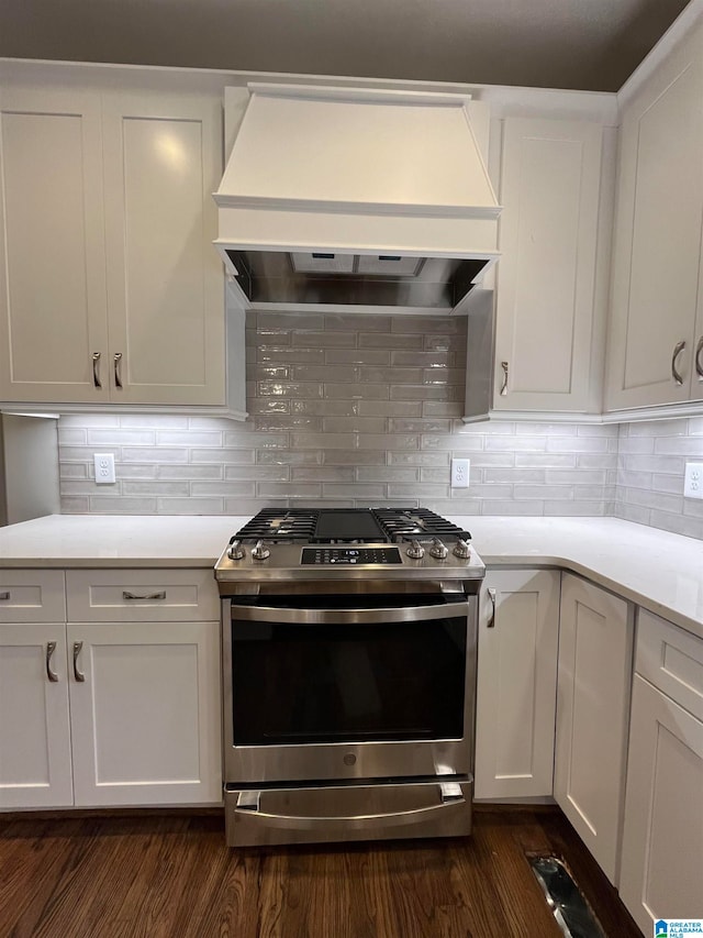 kitchen with gas stove, white cabinetry, dark wood-type flooring, tasteful backsplash, and custom exhaust hood