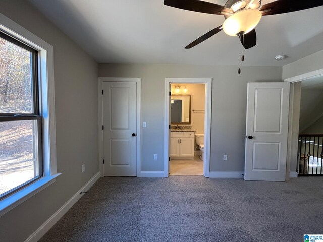 unfurnished bedroom with light carpet, connected bathroom, and ceiling fan