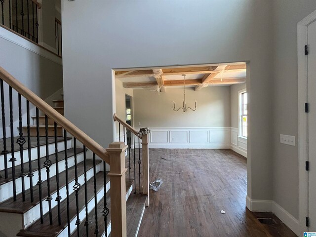 stairs featuring beamed ceiling, wood-type flooring, an inviting chandelier, and coffered ceiling