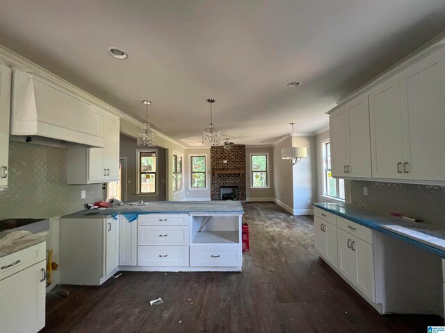 kitchen featuring pendant lighting, custom exhaust hood, a brick fireplace, ornamental molding, and dark hardwood / wood-style flooring