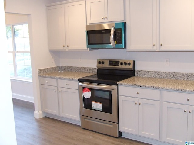 kitchen featuring appliances with stainless steel finishes, white cabinetry, a healthy amount of sunlight, and light wood-type flooring