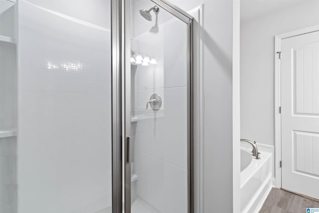 bathroom featuring plus walk in shower and hardwood / wood-style floors