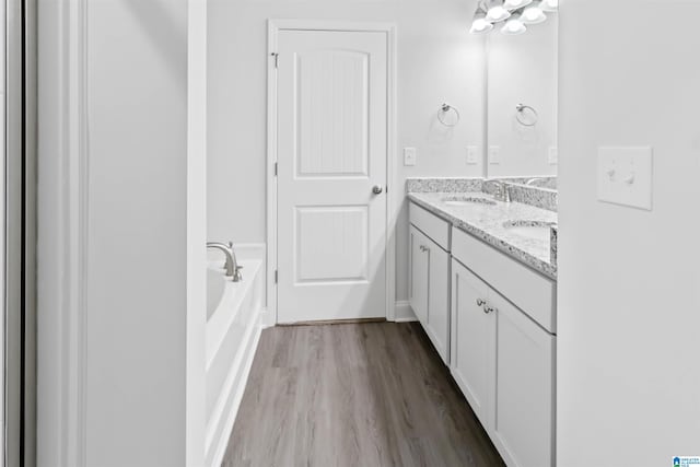 bathroom with hardwood / wood-style flooring, a bath, and dual bowl vanity