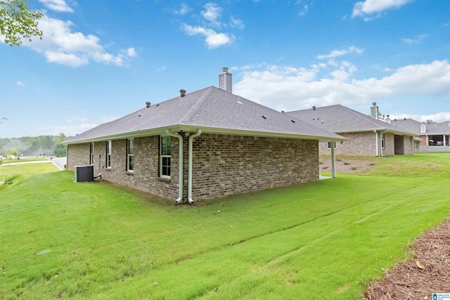 back of property with central AC unit and a yard