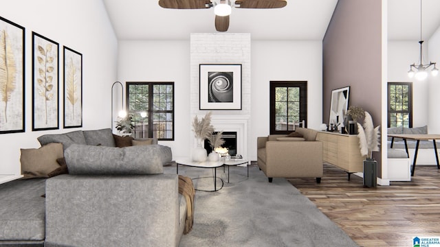 living room with ceiling fan with notable chandelier, hardwood / wood-style floors, a large fireplace, and high vaulted ceiling