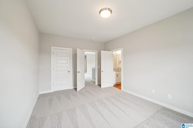 unfurnished bedroom with ensuite bathroom, light colored carpet, and a closet