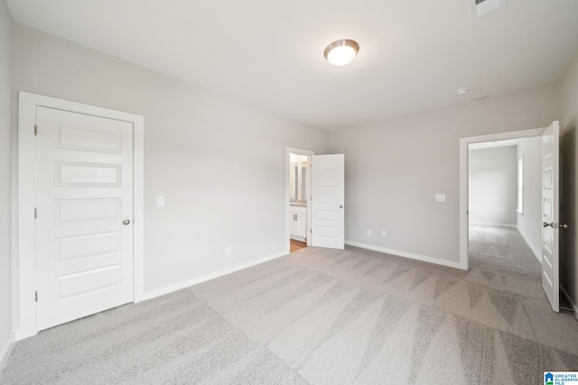 unfurnished bedroom with light colored carpet and connected bathroom