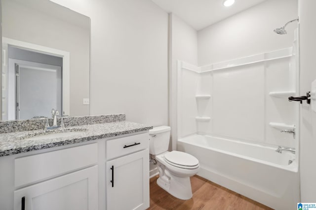 full bathroom with washtub / shower combination, toilet, hardwood / wood-style flooring, and vanity