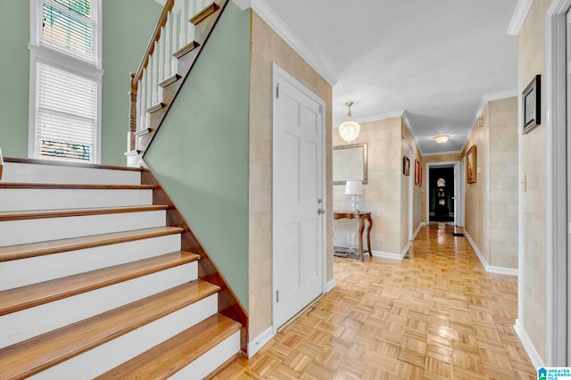 stairway featuring light parquet flooring, a notable chandelier, and crown molding