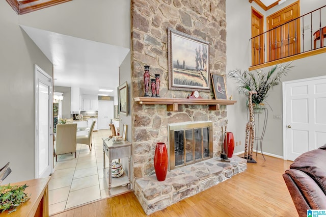 living room featuring a notable chandelier, a fireplace, light tile floors, and a high ceiling