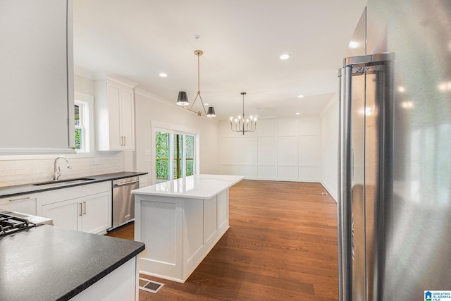 kitchen featuring stainless steel appliances, white cabinetry, a kitchen island, and sink