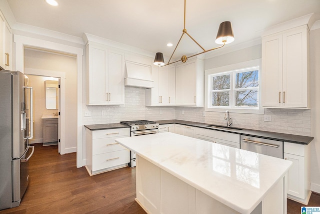 kitchen featuring sink, premium range hood, white cabinetry, appliances with stainless steel finishes, and a kitchen island