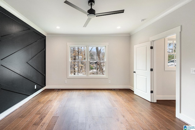 spare room featuring crown molding, ceiling fan, plenty of natural light, and hardwood / wood-style floors