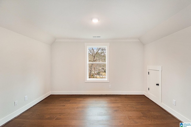 spare room featuring dark hardwood / wood-style floors and vaulted ceiling