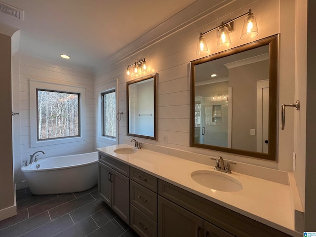 bathroom featuring crown molding, tile floors, dual bowl vanity, and a bathtub