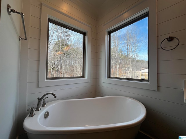 bathroom with a bathtub and wood walls