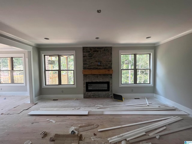 unfurnished living room featuring ornamental molding, a fireplace, a wealth of natural light, and light hardwood / wood-style flooring