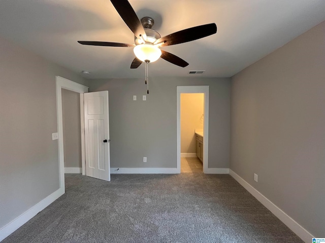 unfurnished bedroom featuring ensuite bath, ceiling fan, and dark colored carpet