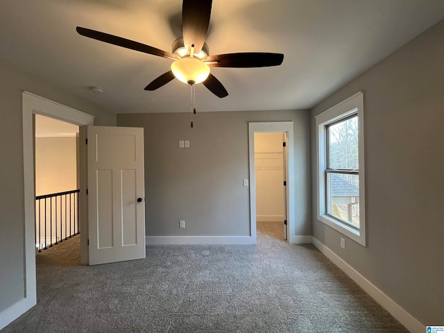 unfurnished bedroom featuring multiple windows, carpet floors, a spacious closet, and ceiling fan