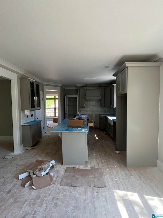 kitchen with a kitchen island, tasteful backsplash, ornamental molding, and gray cabinets