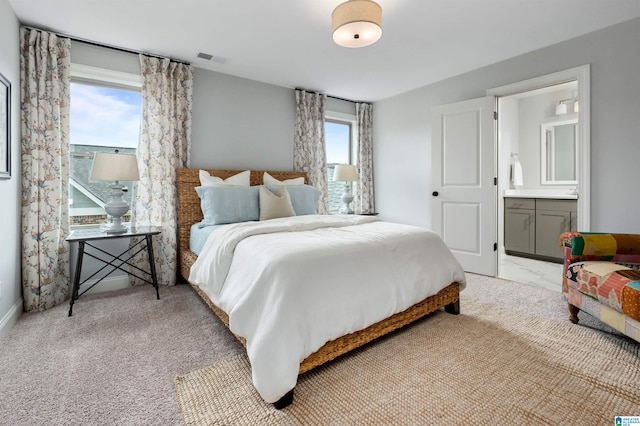 bedroom featuring light colored carpet and connected bathroom