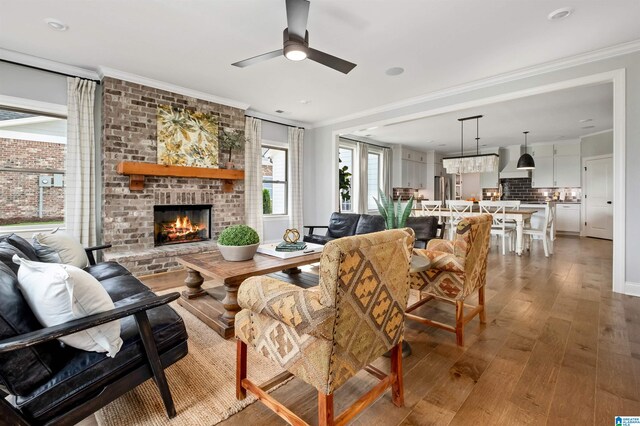 living room with ceiling fan, a fireplace, wood-type flooring, and ornamental molding