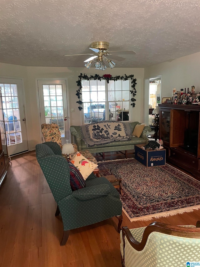 living room with ceiling fan, hardwood / wood-style flooring, and a textured ceiling