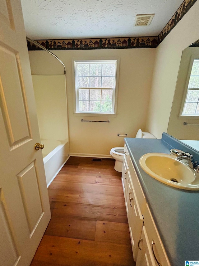 full bathroom with wood-type flooring, bathtub / shower combination, a textured ceiling, toilet, and oversized vanity