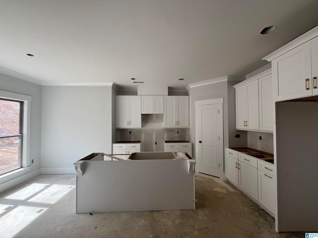 kitchen featuring white cabinets, a center island, and crown molding