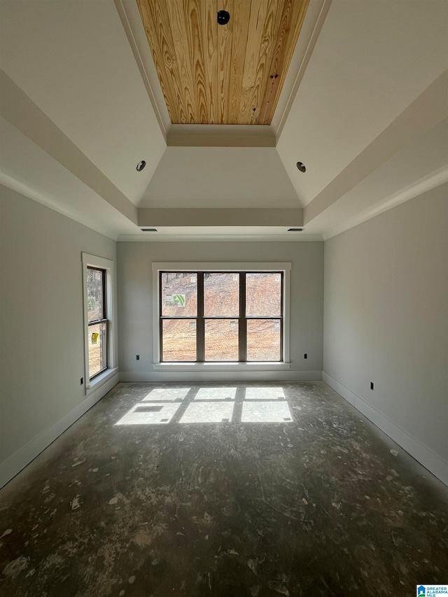 spare room with a tray ceiling, vaulted ceiling, and ornamental molding