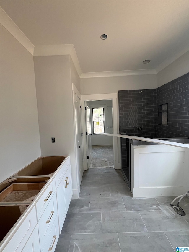 kitchen featuring white cabinets, tile walls, and ornamental molding