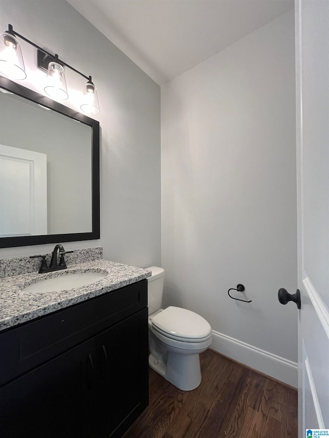 bathroom with hardwood / wood-style floors, vanity, and toilet