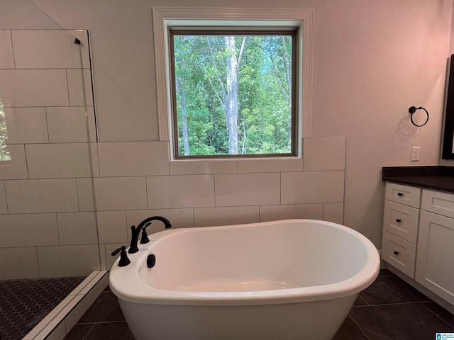 bathroom featuring tile patterned flooring, vanity, tile walls, and independent shower and bath