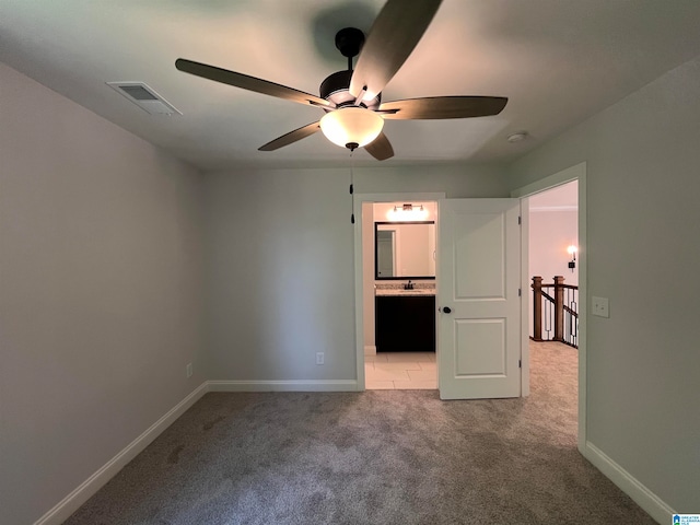 unfurnished bedroom featuring carpet flooring, ensuite bath, ceiling fan, and sink