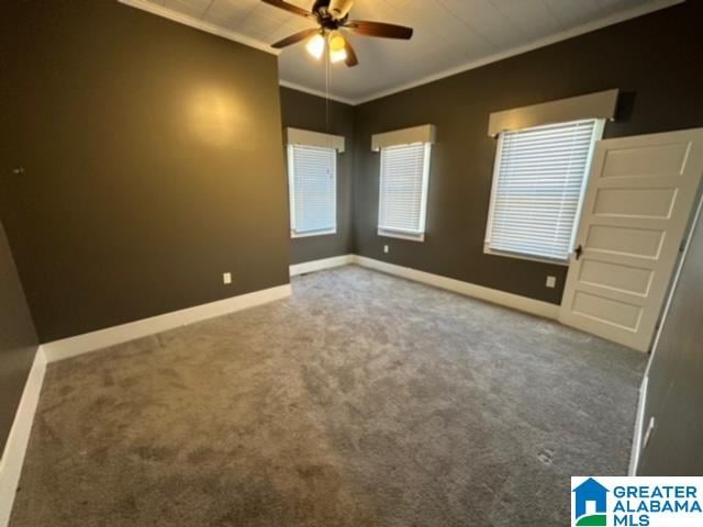 empty room with ornamental molding, ceiling fan, and dark colored carpet