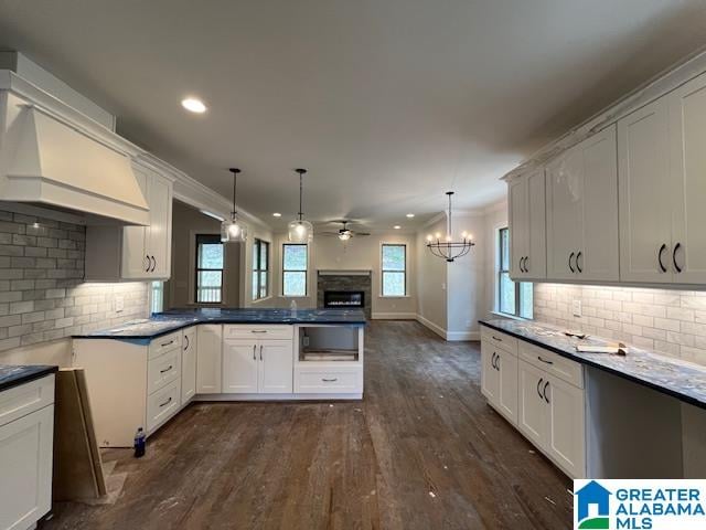 kitchen with backsplash, ceiling fan with notable chandelier, dark hardwood / wood-style flooring, and hanging light fixtures