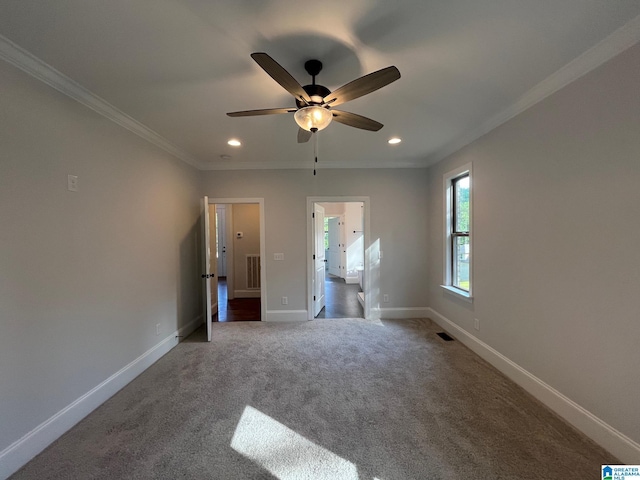 unfurnished bedroom with ceiling fan, ornamental molding, and dark colored carpet