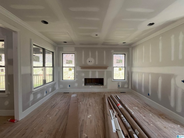 unfurnished living room featuring plenty of natural light, hardwood / wood-style floors, and ornamental molding